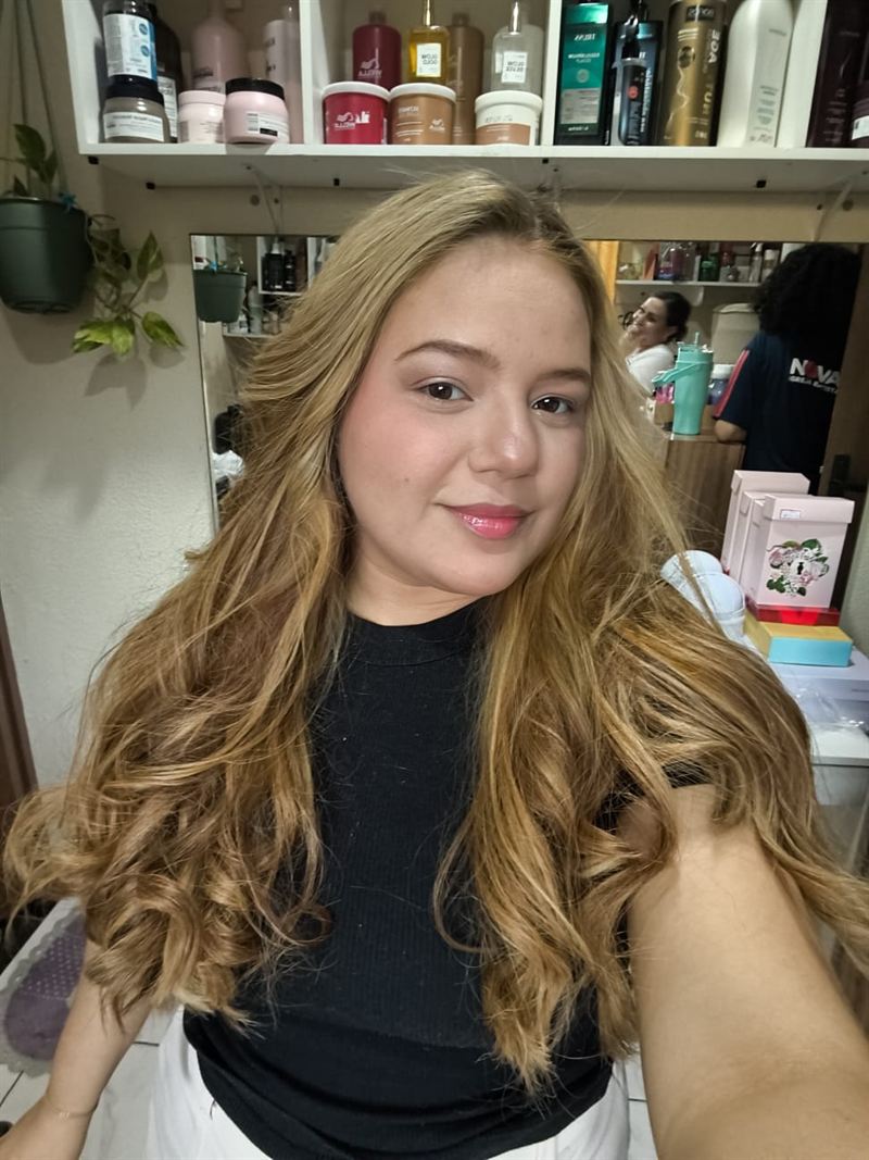 Cliente sorrindo com cabelo loiro ondulado e finalizado no Studio Helena Fernandes em Manaus
